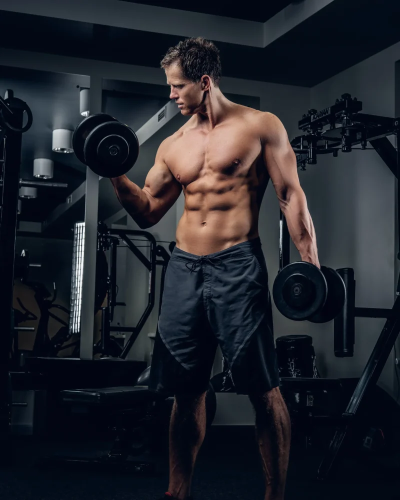 full-body-portrait-athletic-shirtless-male-doing-biceps-workouts-with-dumbbells-gym-club